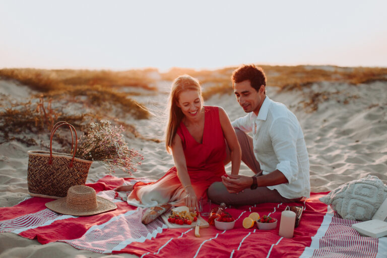 couple en train de prendre l'apéritif au Cap Ferret sur un plaid rouge au coucher du soleil