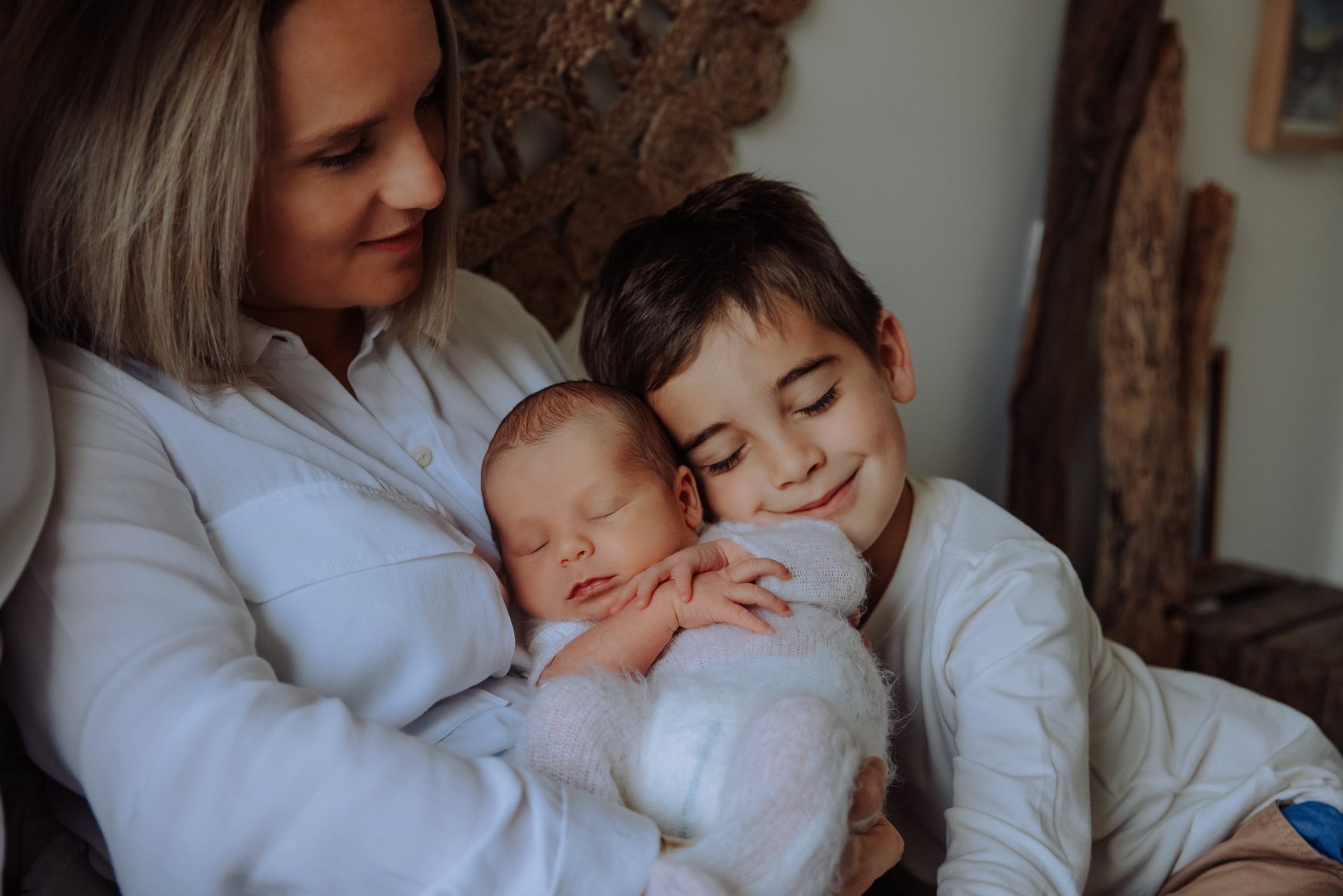 Ainé en train de faire un calin à son petit frère dans les bras de sa maman